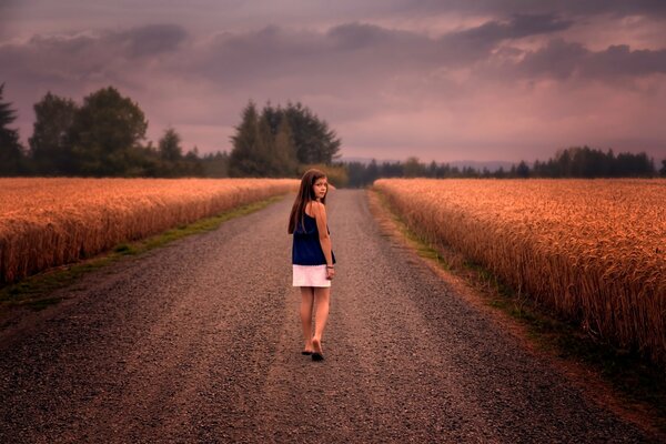 Jeune fille marche pieds nus sur la route dans le champ