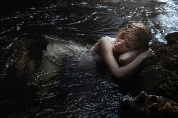 A girl in a white dress lies in the river