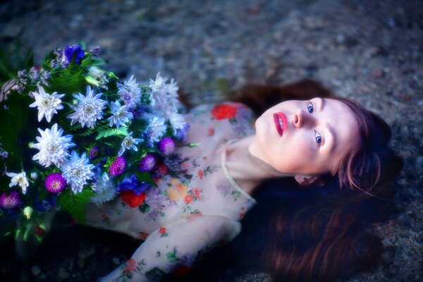 Schönes Mädchen liegt im Wasser mit Blumen