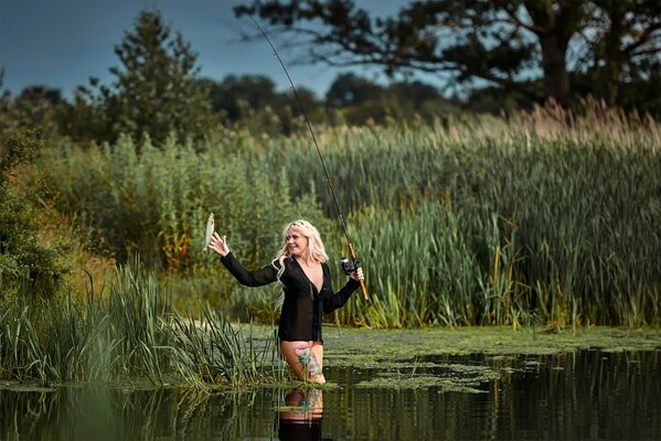 Fille blonde pêche joyeusement un poisson