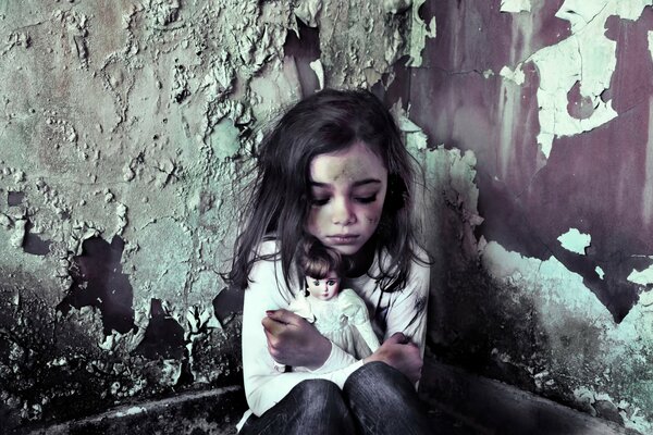 Девочка с куклой у грязной стены