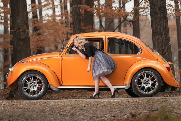 The blonde looks in the mirror of an orange Volkswagen