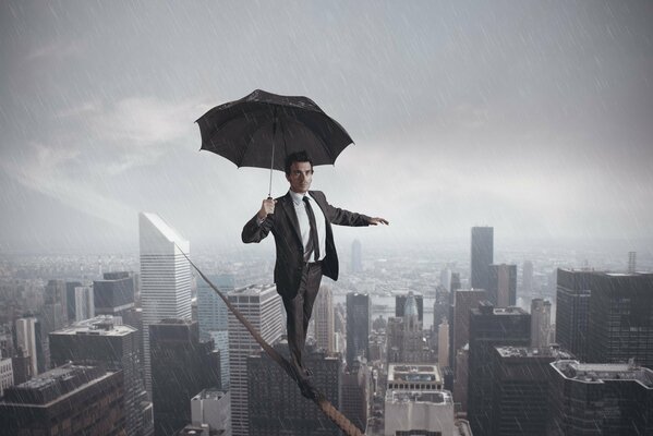 Ein Mann mit einem Regenschirm geht im Regen an einem Seil entlang