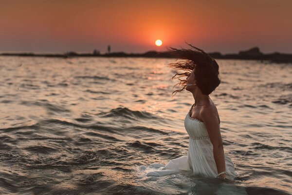 Chica en el agua admirando la puesta de sol