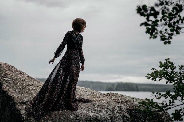 Chica con un hermoso vestido en una piedra junto al mar