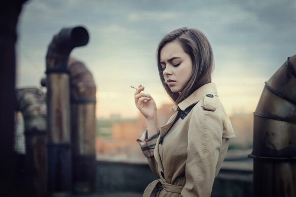 The girl Ekaterina Kuznetsova on the city roof with a cigarette