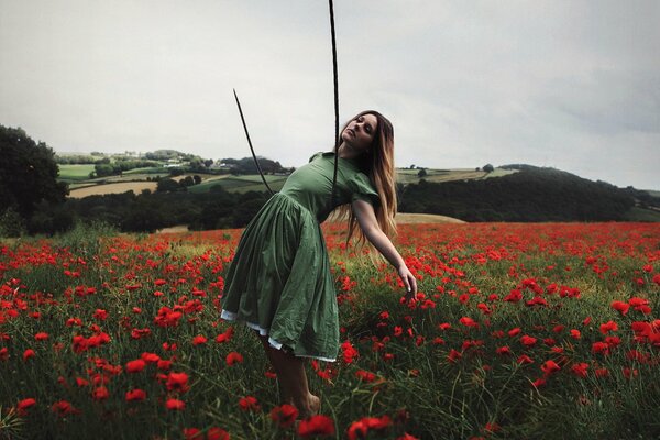 Ragazza in vestito verde nel campo con i papaveri