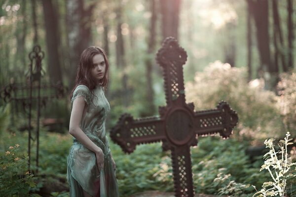 Una niña Mira una Cruz en un cementerio