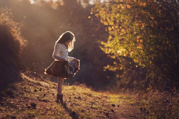 Девушка в красивом платье в осеннем лесу. Солнечные лучи