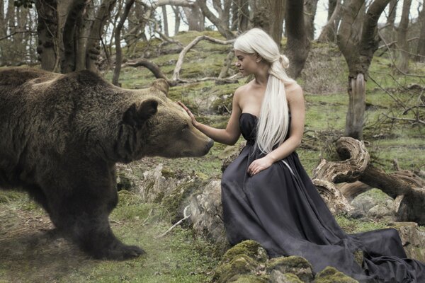 Mädchen im schwarzen Kleid im Wald streichelt einen Bären