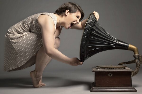 A girl screams into a gramophone on a dark background