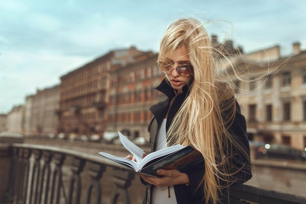 Ragazza che legge un libro per strada