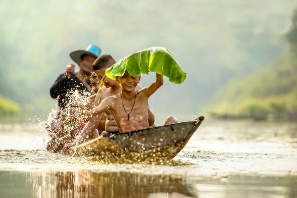 Kinder segeln auf einem Boot und spritzen im Wasser