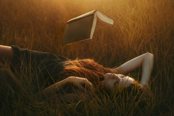 A girl reads a floating book lying in the grass