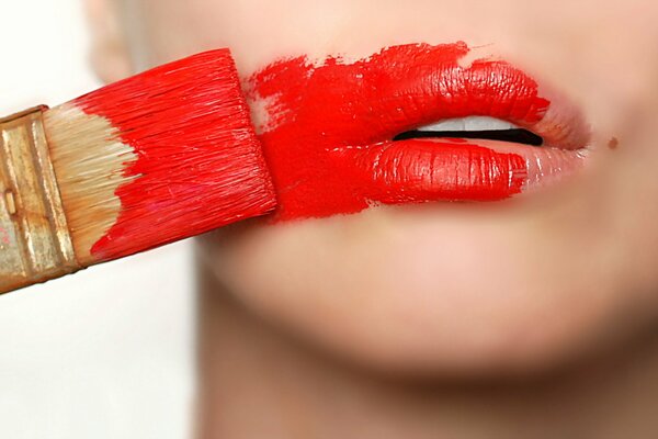 La jeune fille met du rouge à lèvres de la peinture