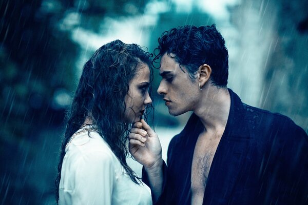 A beautiful couple stands romantically in the rain