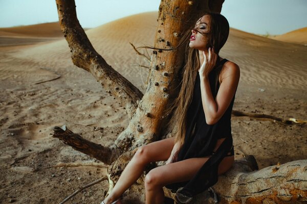 Girl with long hair on a tree in the desert