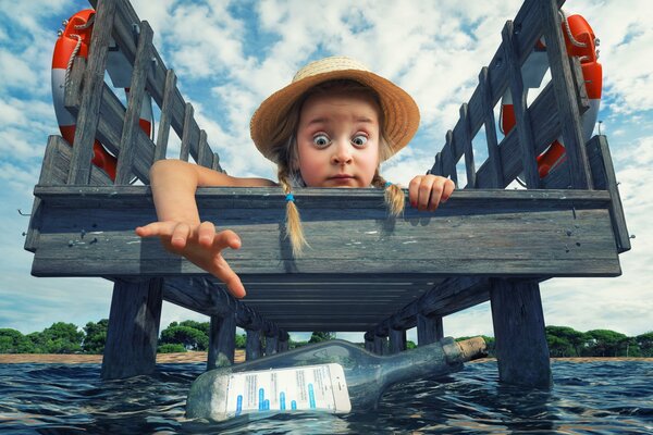 Girls with pigtails in a hat catches a bottle with a phone