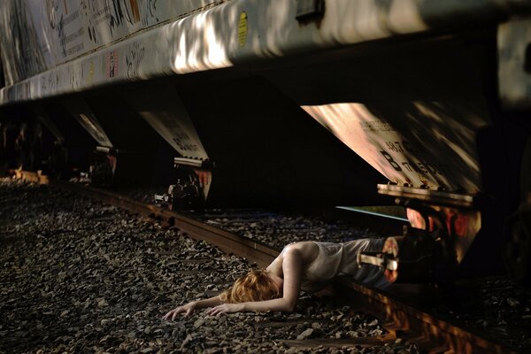 Chica acostada en las vías bajo el tren