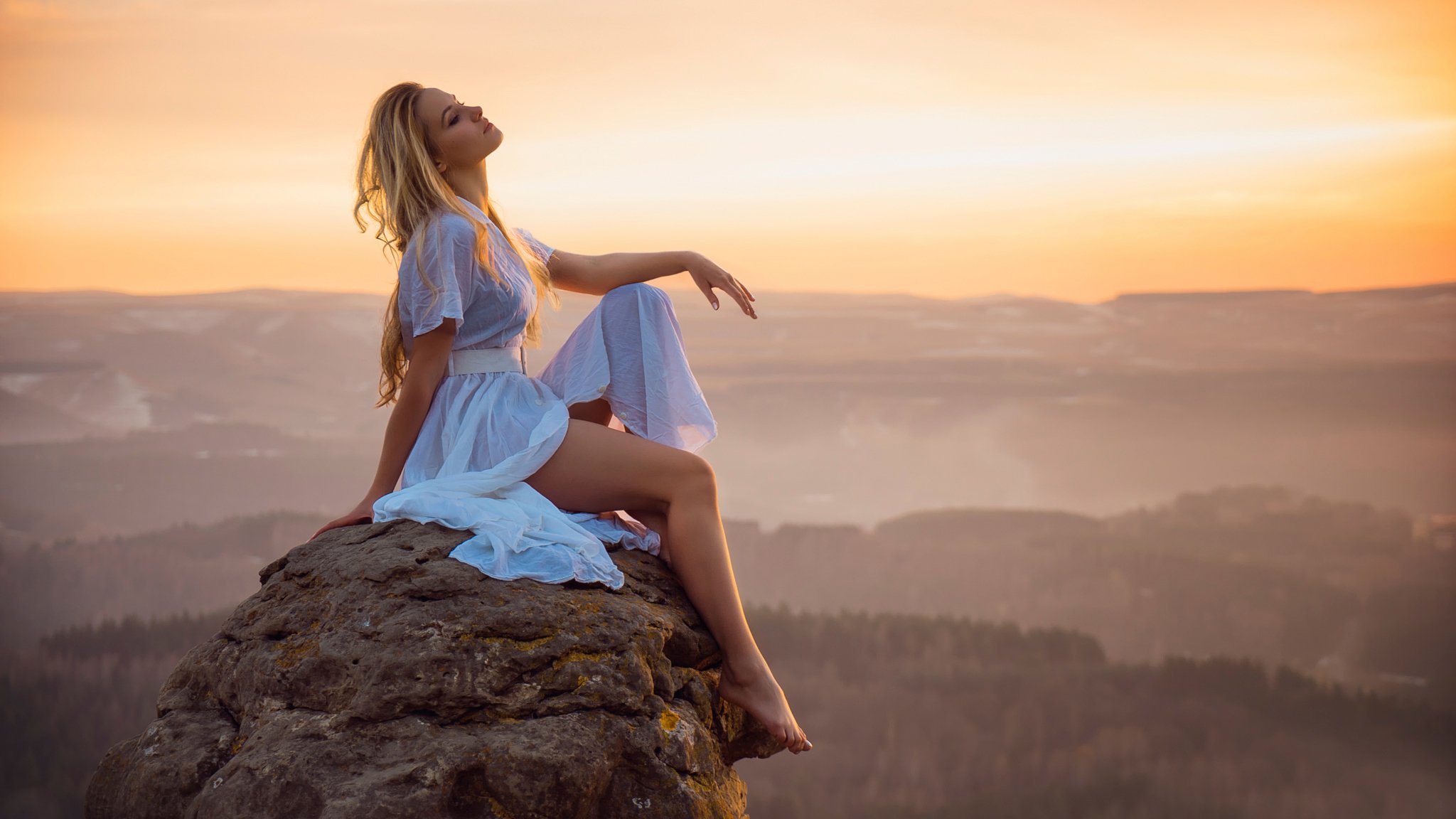 l érotisme la jeune fille les pieds coucher de soleil la pierre la hauteur le lointain le paysage la vue