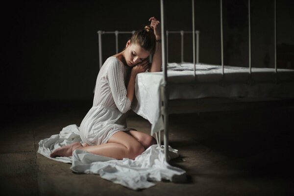 Girl in white on the floor by the bed