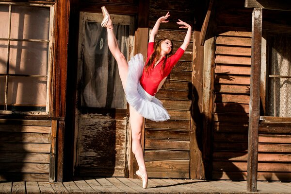 Ballerina tanzt vor dem Hintergrund eines Holzhauses