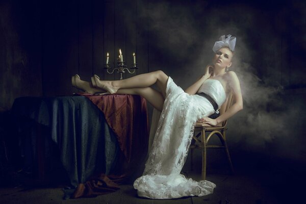 A beautiful girl in a hat is sitting on a chair with her legs on the table