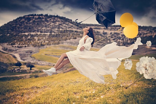 A girl in a white dress is flying on balloons from a strong wind