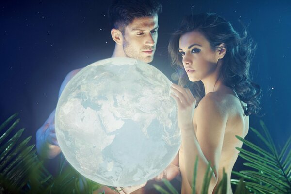 A guy and a girl hold a night light in the form of a planet