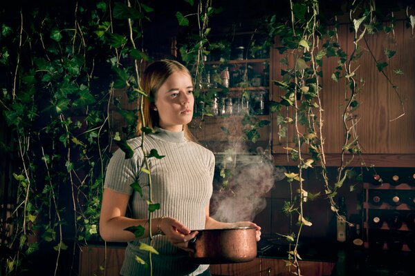 A girl with a pot on her hands on a background of plants