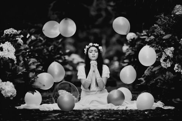 Foto en blanco y negro de una chica con un vestido blanco entre las bolas