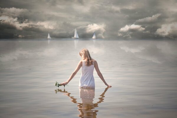 Ragazza in piedi in acqua. Vele in mare