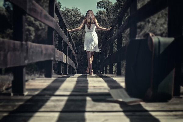 Caminar por el puente. Chica en vestido blanco