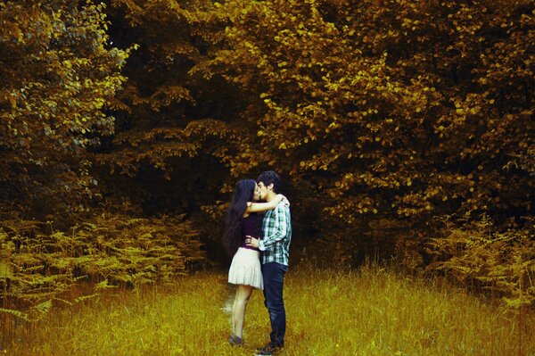 Chico y chica abrazándose en el bosque de otoño