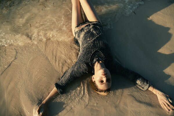 A beautiful model is lying on the sand