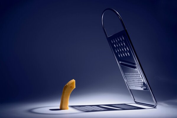 A piece of cheese looks at the grater