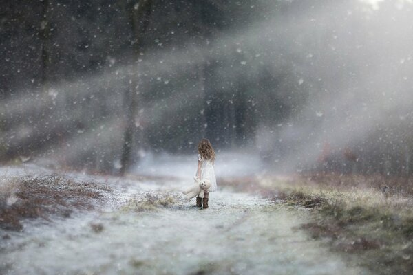 Ragazza in abito bianco che cammina sotto la neve