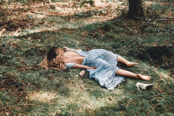 Chica en un vestido sin zapatos yace en la hierba