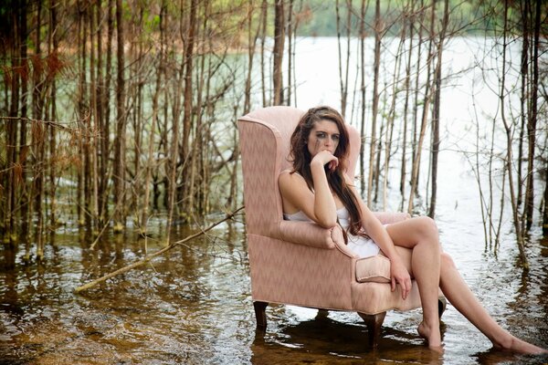 Chica en una silla en el fondo del bosque