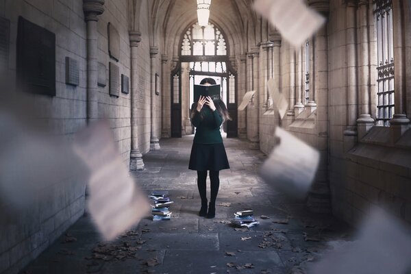 A girl in a dark dress with a book by her face