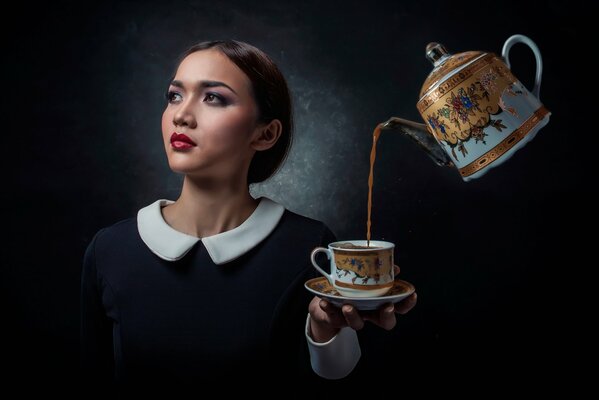 The teapot pours the girl a drink on a black background
