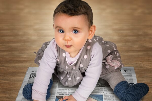 Une petite fille est assise sur le journal