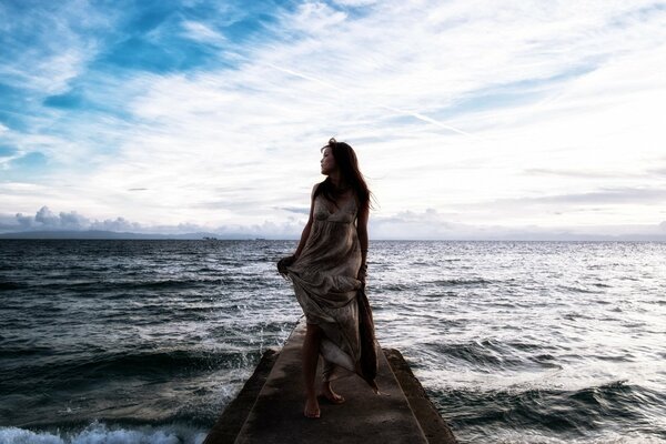 Mädchen im Kleid steht am Pier