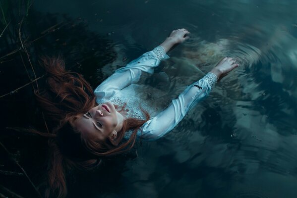 A girl in a white shirt lies in the water up to her waist