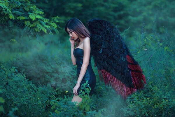 A girl with black wings in the forest