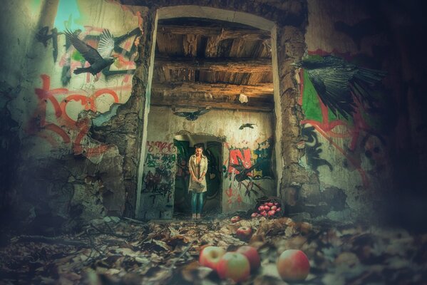 A girl on the threshold of an abandoned house, apples on the ground and black birds