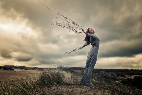 A girl in a field with roots instead of hands