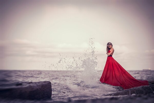 Chica en vestido rojo en la orilla del mar