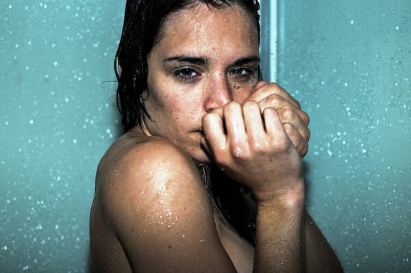 A girl with dark hair is standing under the shower