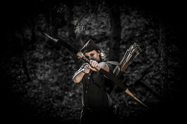 A girl on a dark background shoots an arrow